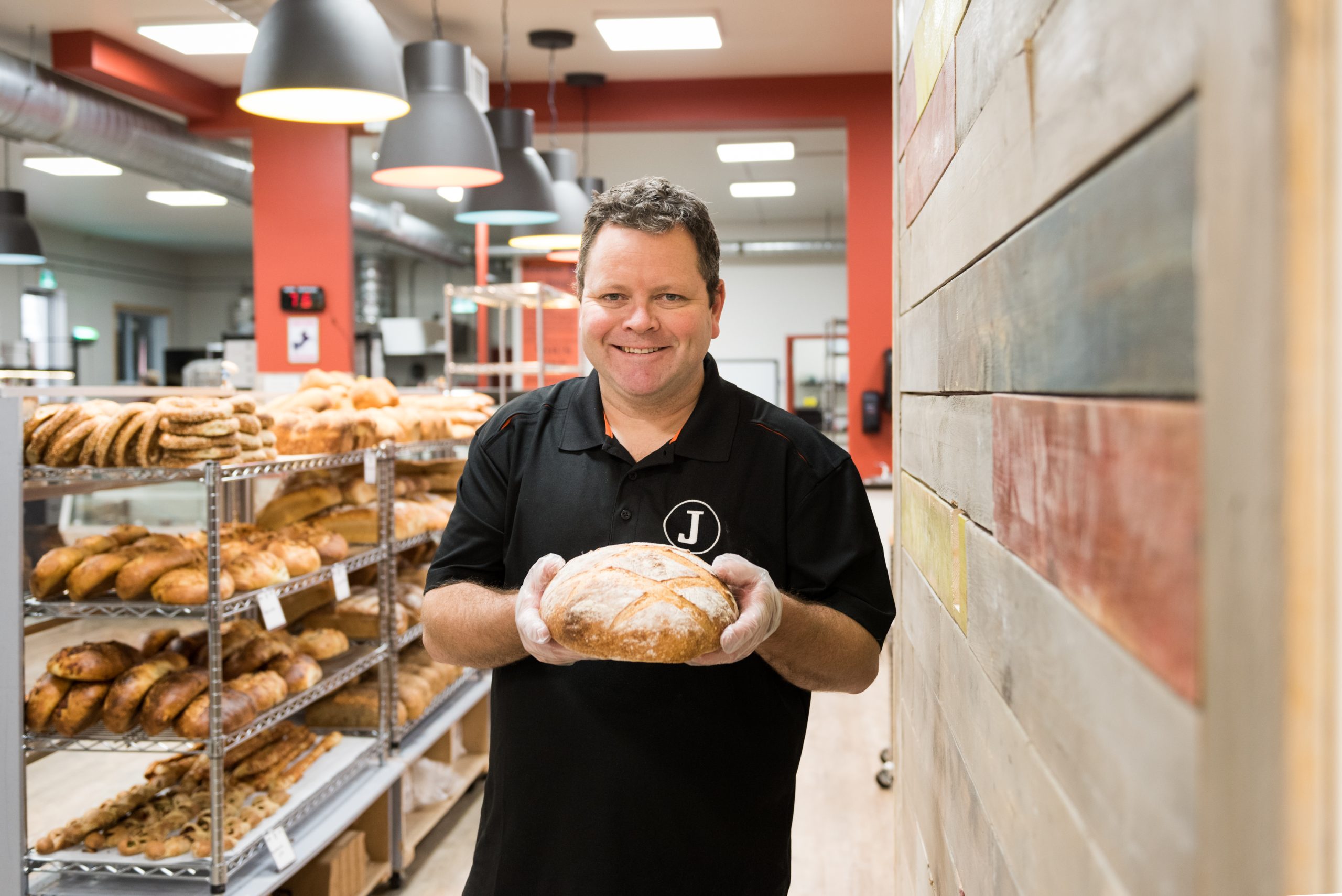 Boulanger dans sa boulangerie tenant un pain dans ses mains